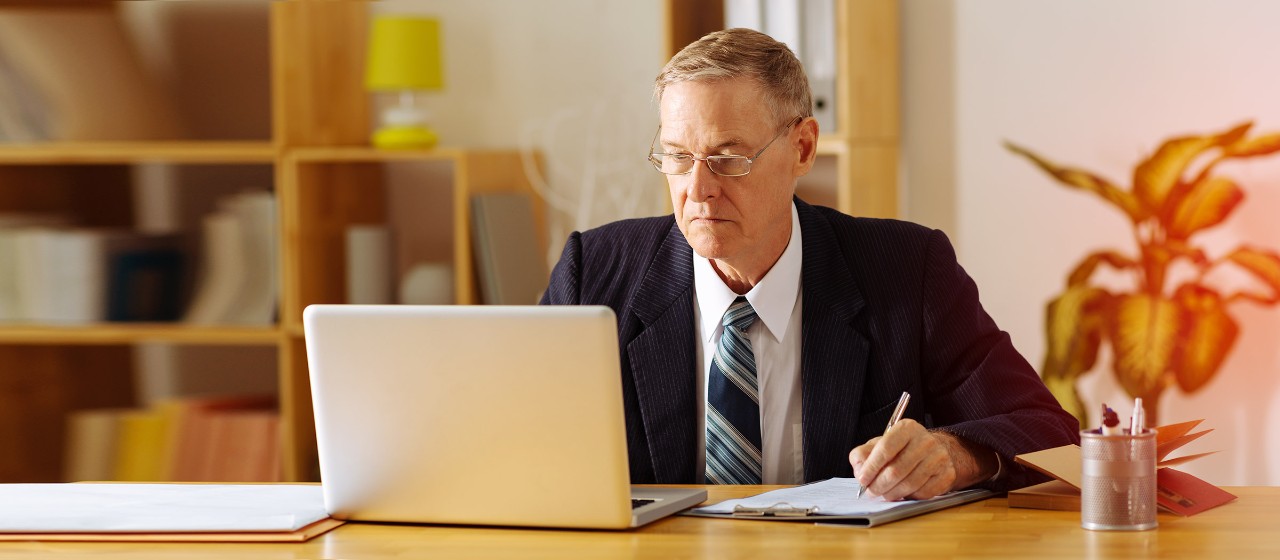Mann im Anzug am Schreibtisch mit Laptop
